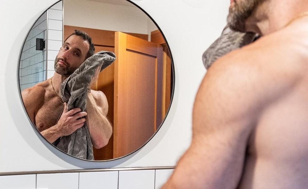 Man practicing Ayurvedic self-care routine in mirror for daily balance & wellness