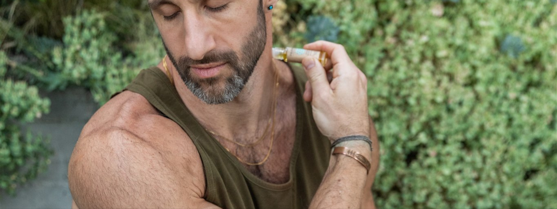 Muscular man applying Ayurvedic herbal oil to neck for muscle tension relief and recovery support