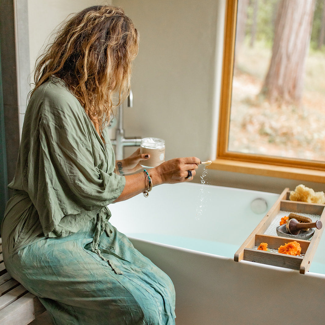 Woman in a green robe preparing a PAAVANI Ayurveda Coconut Milk Bath