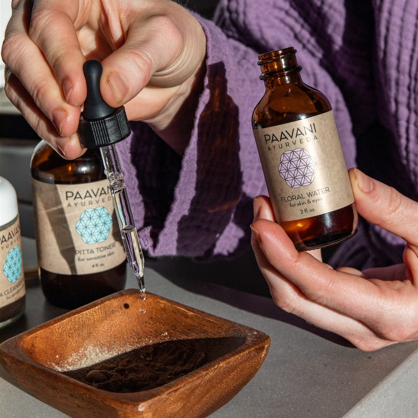 Person in a purple robe preparing their PAAVANI Cleanser & Mask ritual