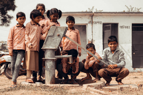 Indian kids standing next to water well