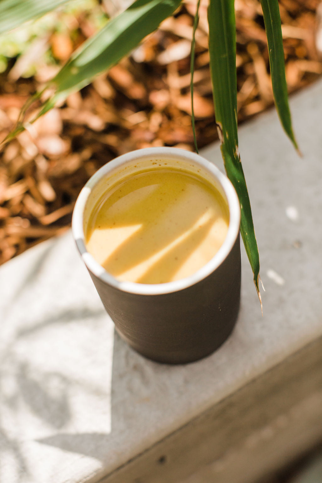 Warm cup of Ayurvedic golden milk on wooden table with cinnamon & turmeric