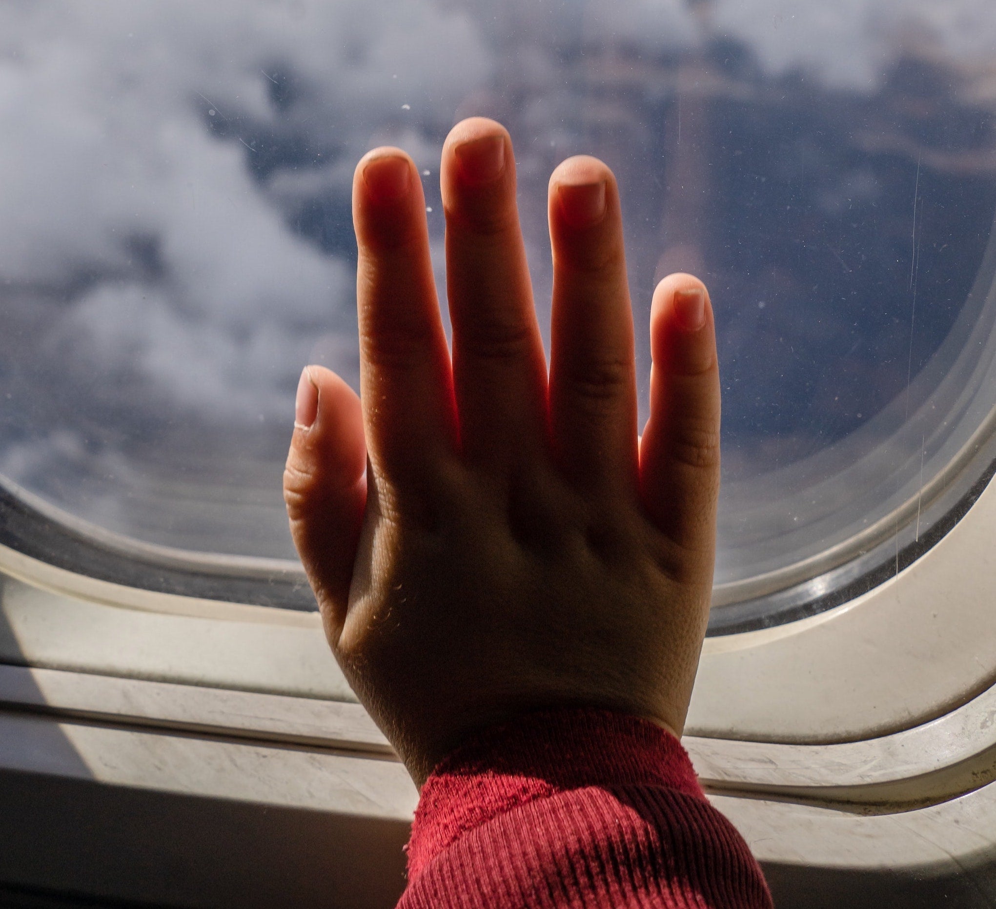 Mother & child holding hands by airplane window, embodying Ayurvedic calm during travel