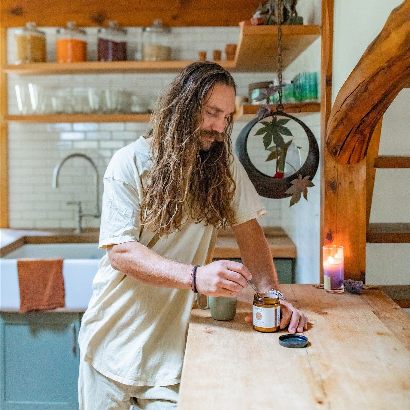 Man with long hair preparing ashwagandha churna in a rustic kitchen.