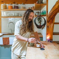 Man with long hair preparing ashwagandha churna in a rustic kitchen.
