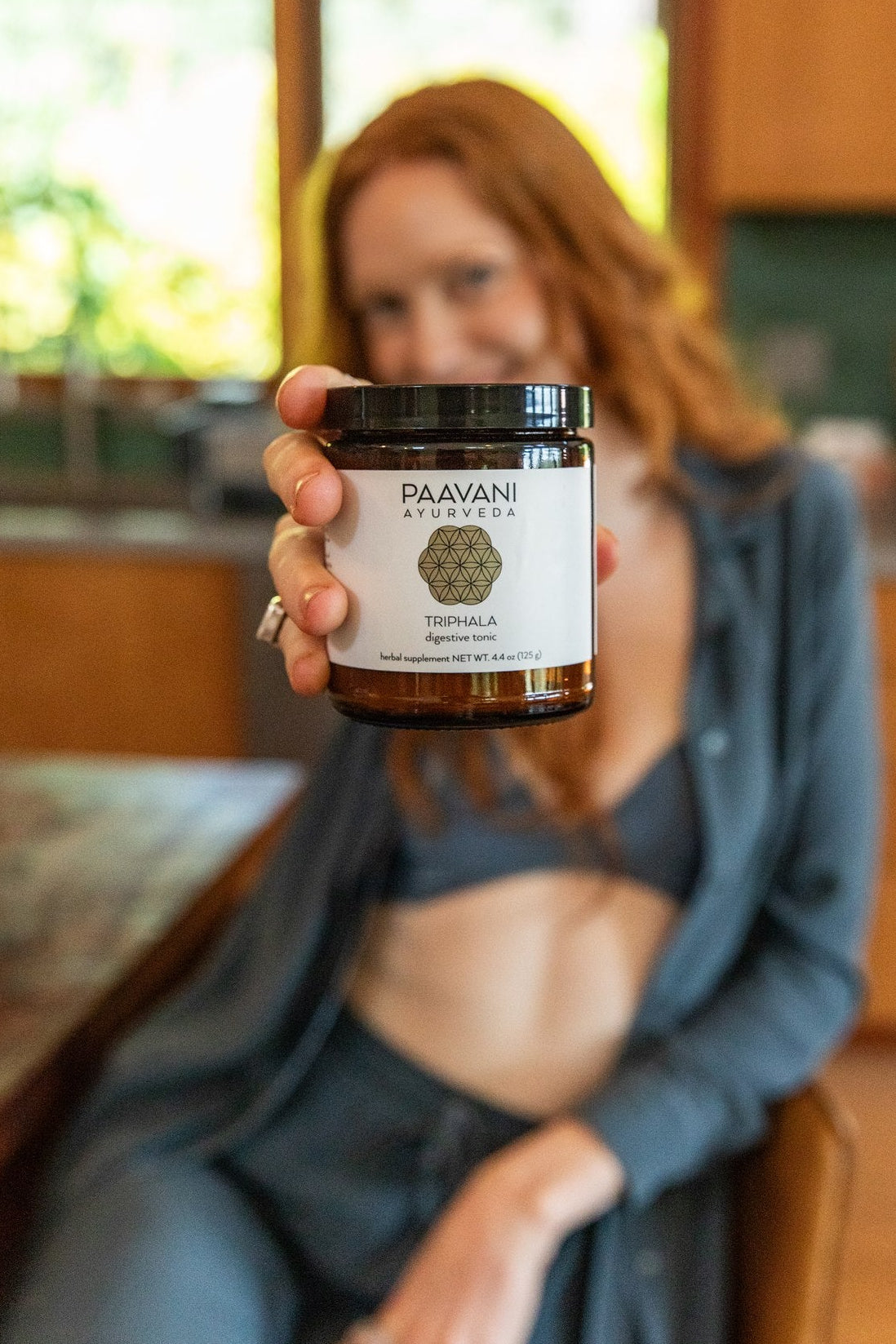Person holding a jar of Paavani Ayurveda product in a kitchen setting