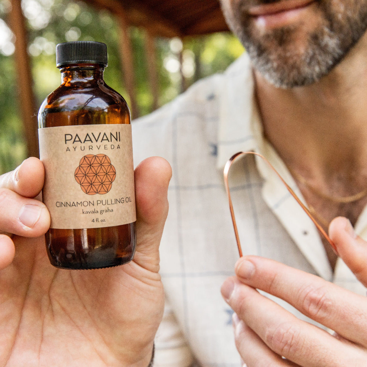 Person holding a bottle of Paavani Ayurveda cinnamon pulling oil  outdoors.
