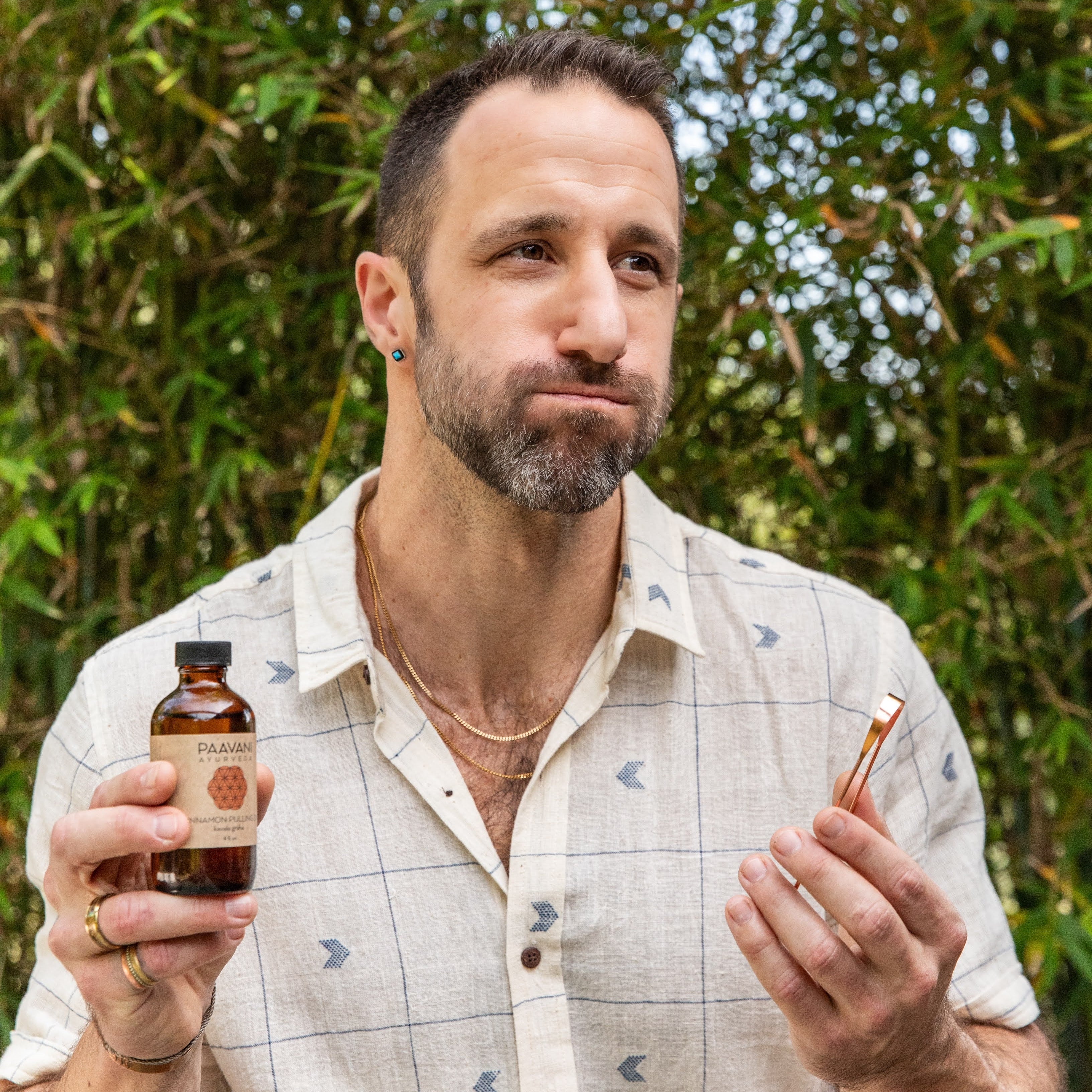 Man holding a bottle and a pen against a natural background