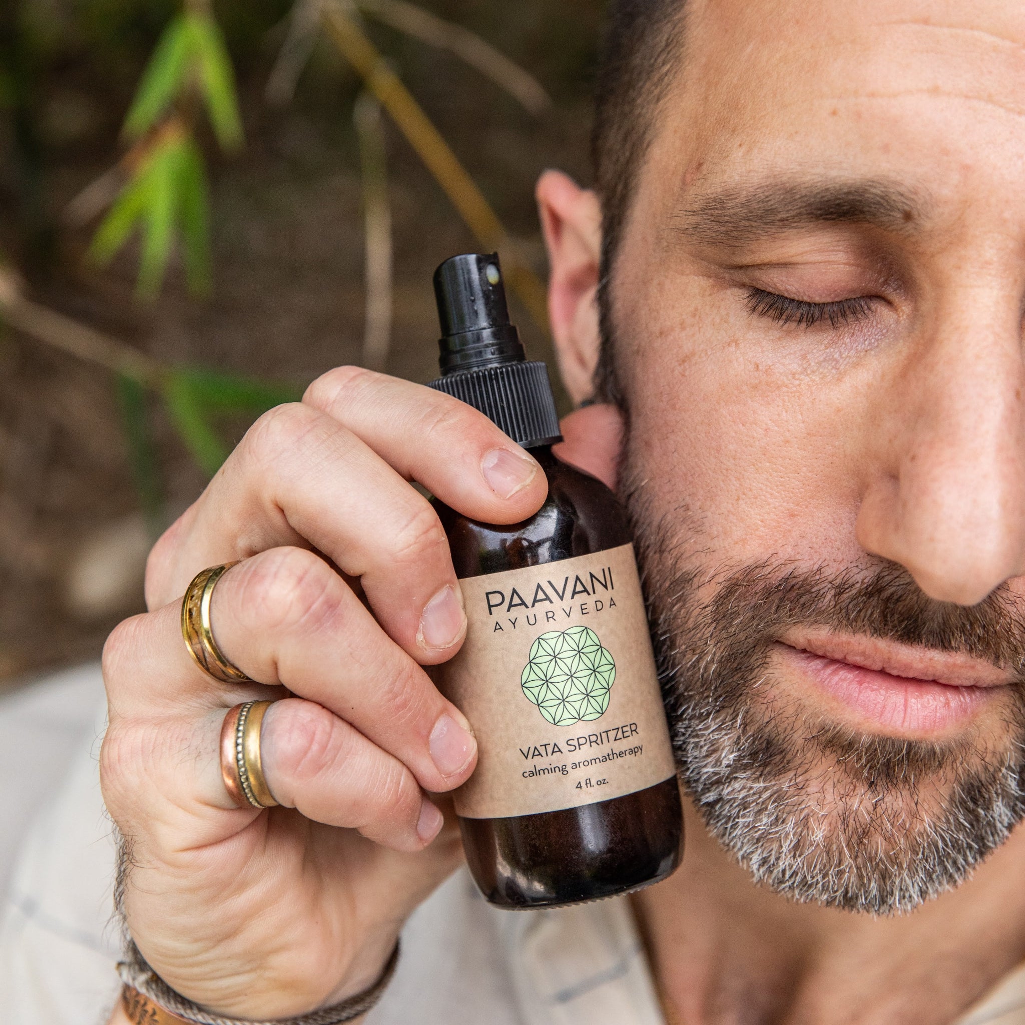 Man holding a bottle of Paavani Ayurveda product aromatherapy spritzer with a natural background