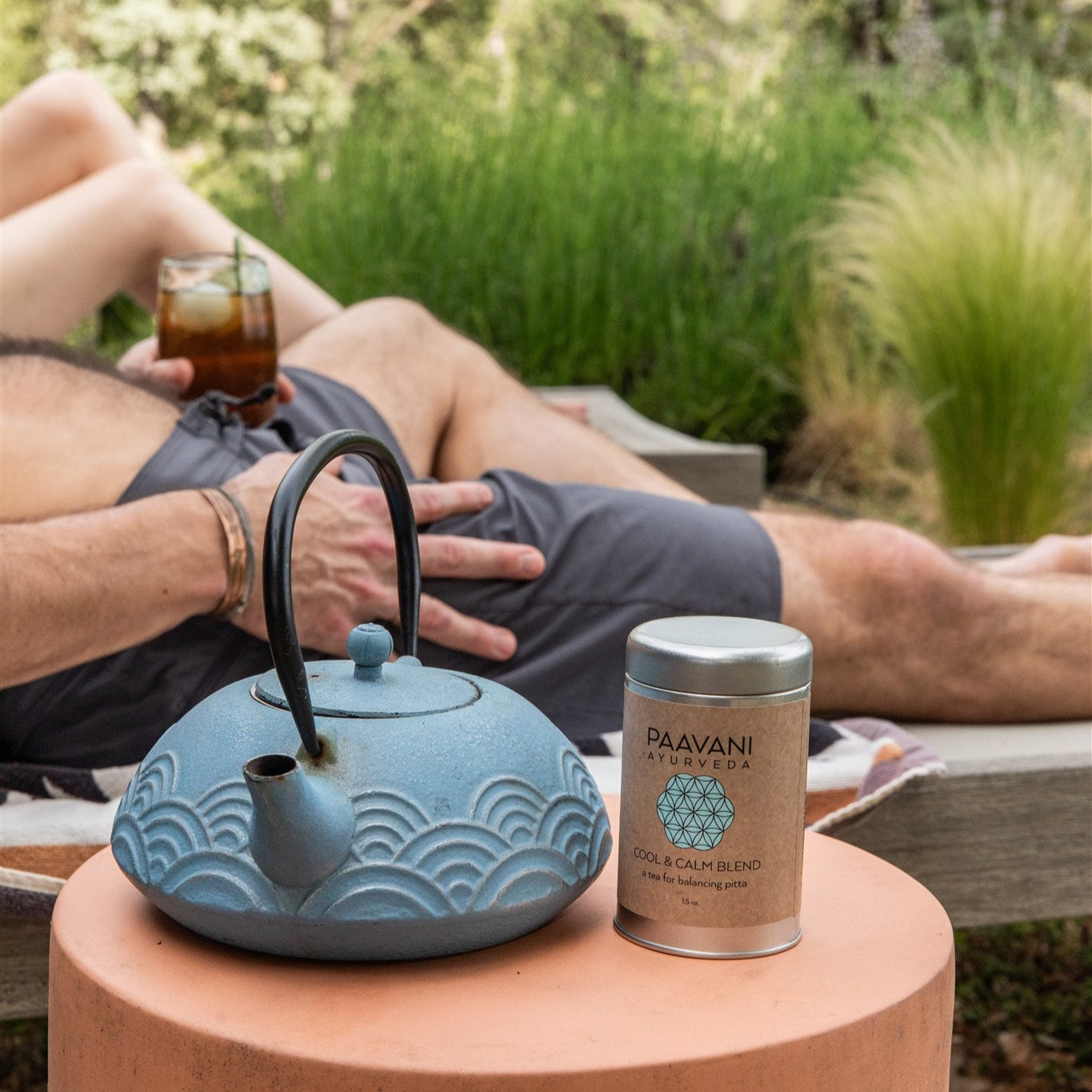 Person relaxing outdoors with a blue teapot and Paavani cool & calm blend tea